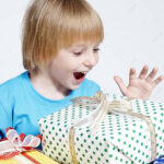 pngtree small child holding presents against a bright backdrop photo image 1114807 e1703174504408